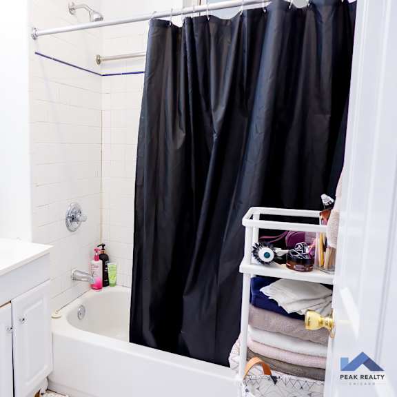 a bathroom with a white sink and black shower curtain.