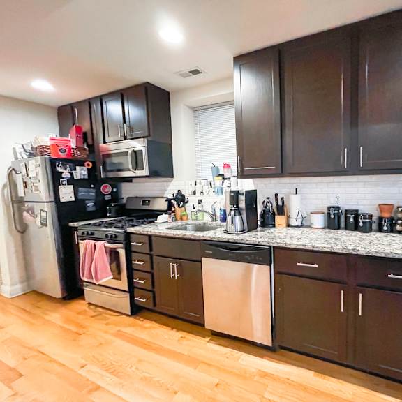 a kitchen with dark brown cabinets and a white tile backsplash.