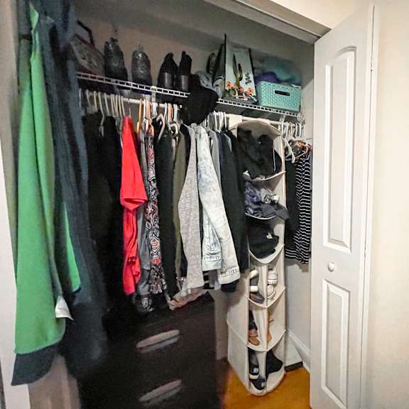 a white closet with clothes hanging on a rail.