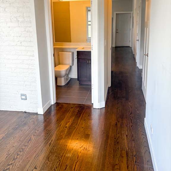 a white bathroom with a toilet and sink is open to a hallway.