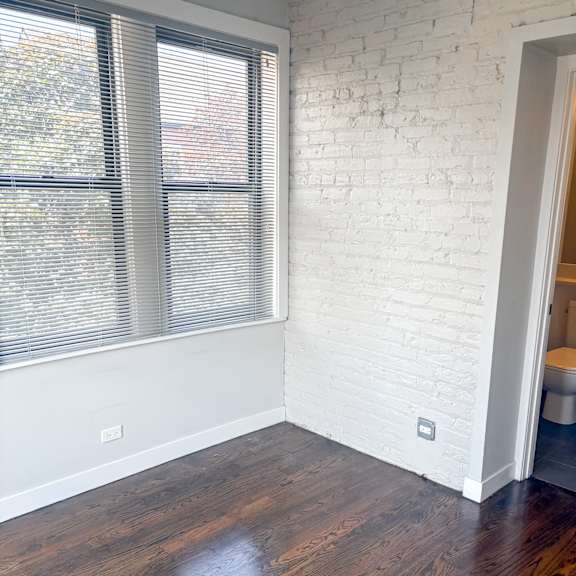 a room with a white brick wall and wooden floors.