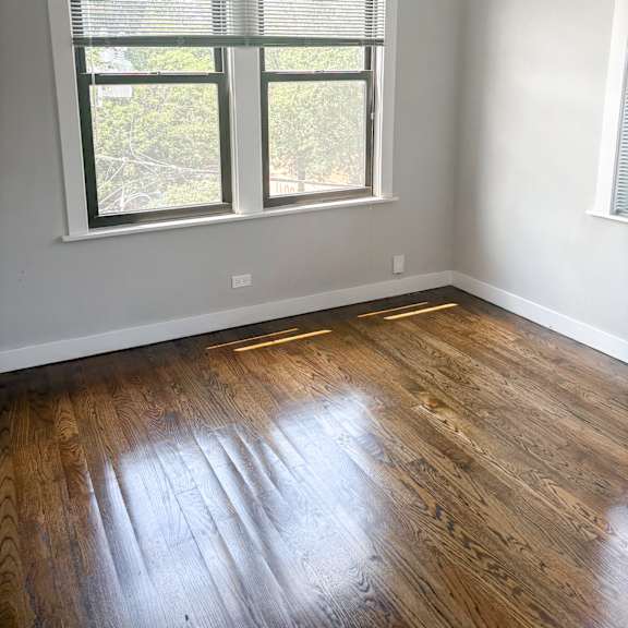 a room with a window and wooden flooring.