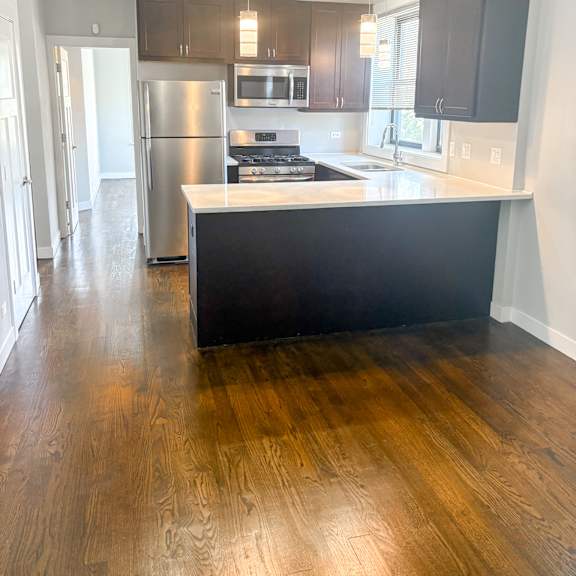 a kitchen with a black counter top and wooden floors.