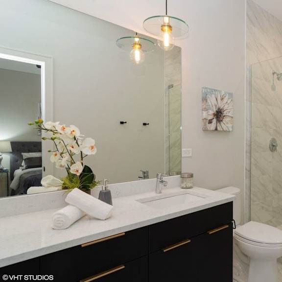 a bathroom with a white toilet, a sink with a mirror above it, and a glass shower door.