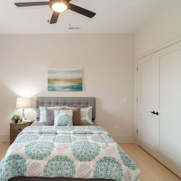a bedroom with a bed, a ceiling fan, and a painting on the wall.