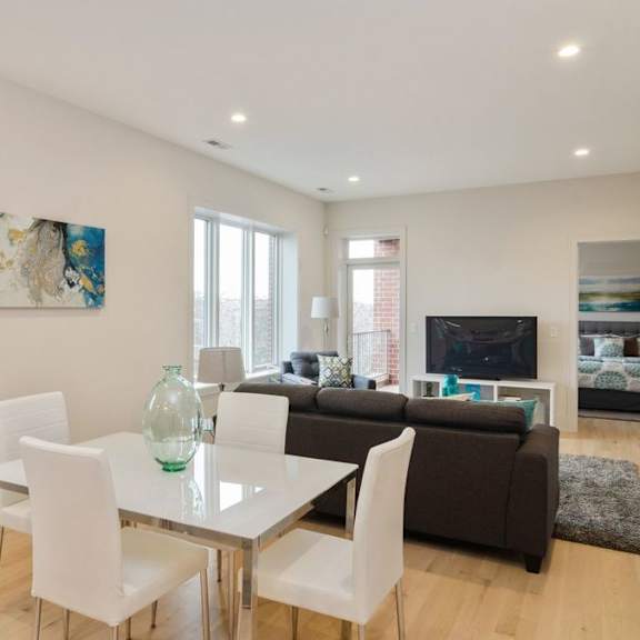 a modern living room with a glass dining table and white chairs.