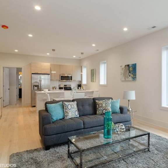 a modern living room with a grey couch and a glass coffee table.