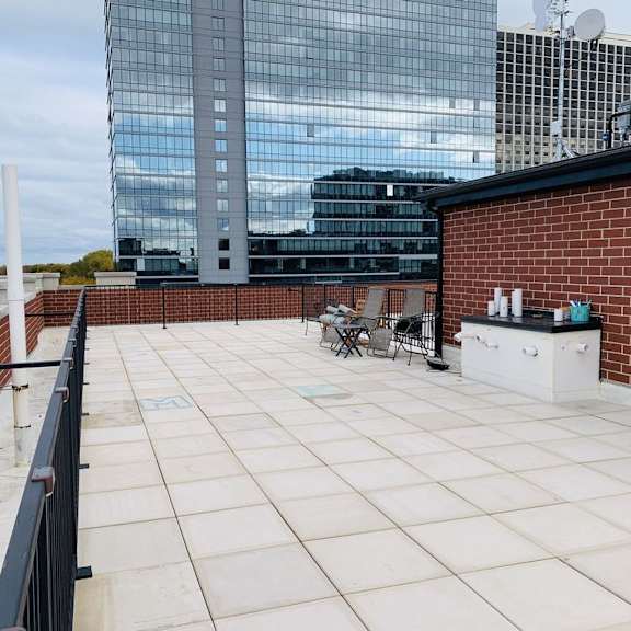 a rooftop patio with a table and chairs overlooking a cityscape.