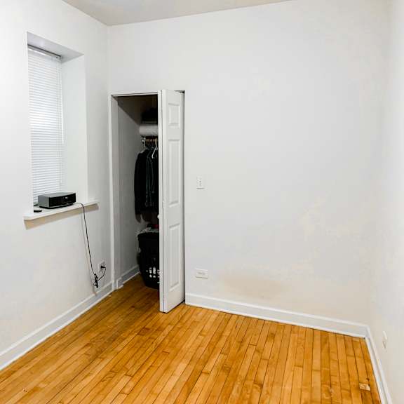 a room with a wooden floor and a white wall with a doorway leading to another room.