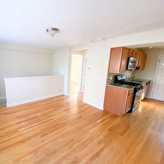 an empty kitchen and living room with wood flooring