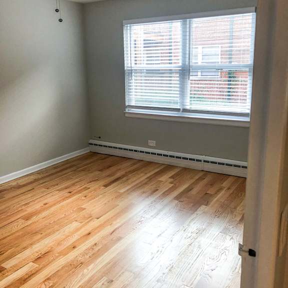 a room with a ceiling fan and wooden flooring.