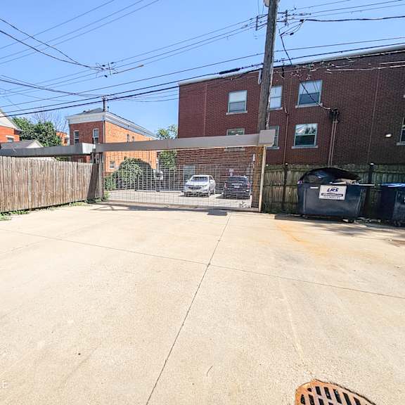 a driveway with a fence and brick buildings on either side of it