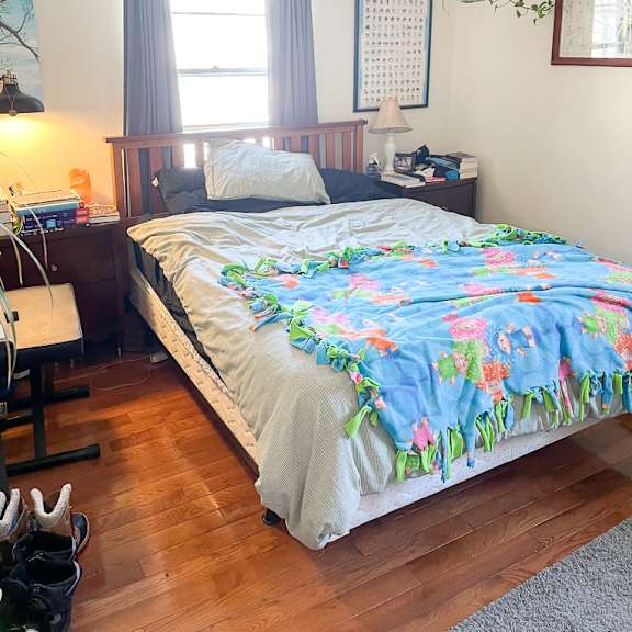 a bed with a blue blanket and a white pillow is in the center of the room.