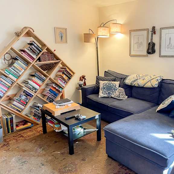 a living room with a blue couch, a coffee table, and a bookshelf filled with books.