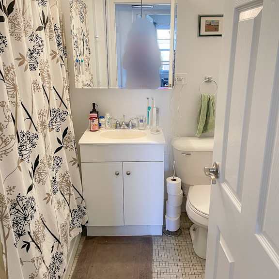 a white bathroom with a floral shower curtain.