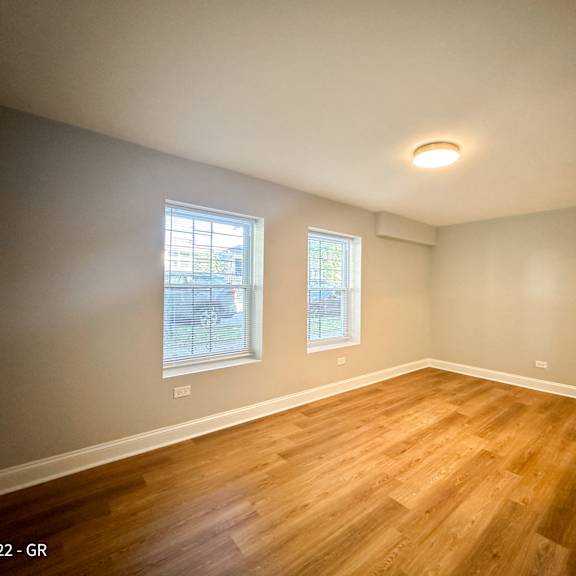 a room with wooden floors and two windows.