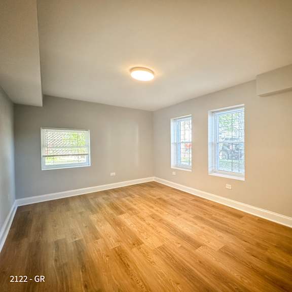 empty room with wooden floors and two windows.