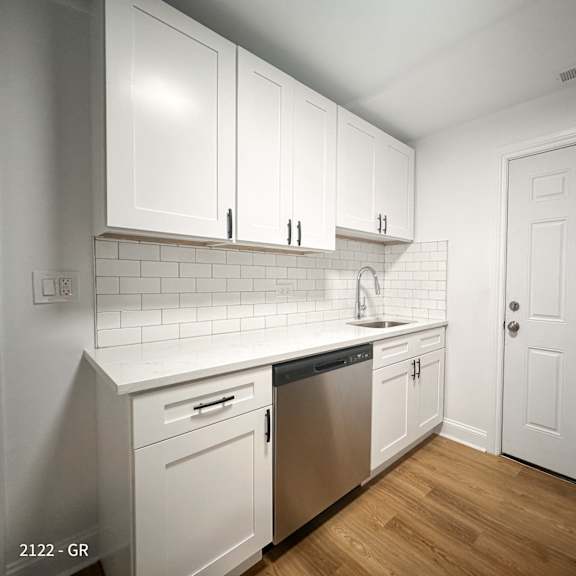 a kitchen with white cabinets and a white door.
