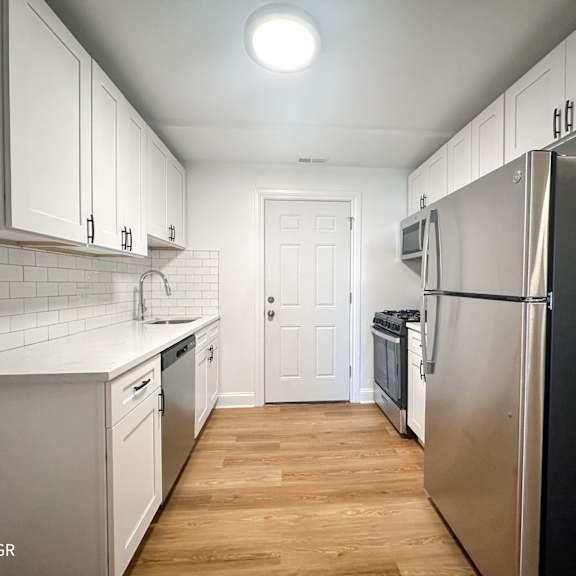 a kitchen with white cabinets and a black refrigerator.