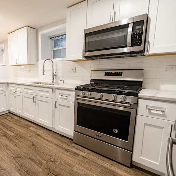 a kitchen with white cabinets and stainless steel appliances.