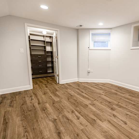 a room with wooden flooring and a window with blinds.