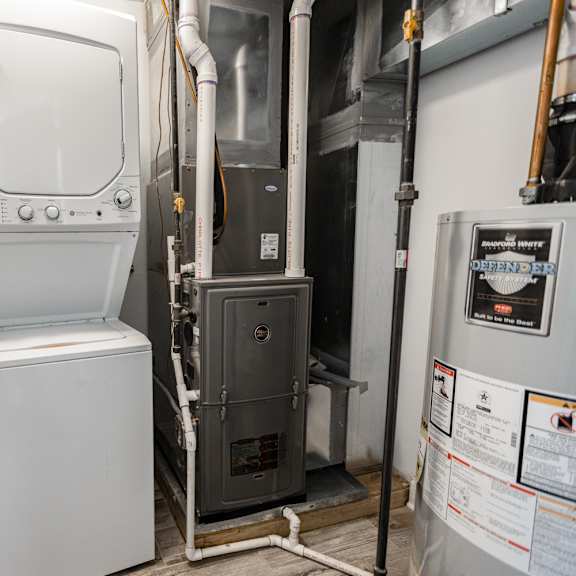 a white tankless water heater sits next to a wall.