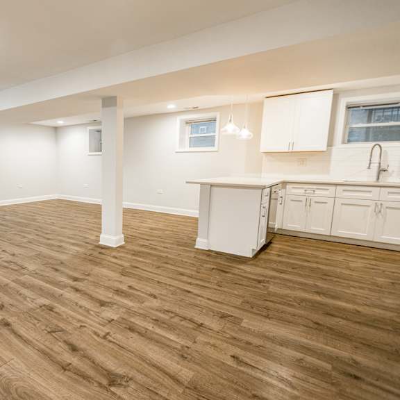 a spacious room with wooden flooring and white cabinetry.