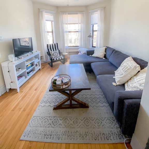 a living room with a grey couch, a wooden coffee table, and a television.