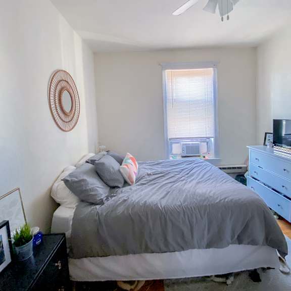 a bedroom with a bed, dresser, and ceiling fan.