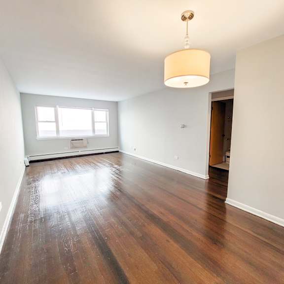a room with wooden floors and a hanging light fixture.