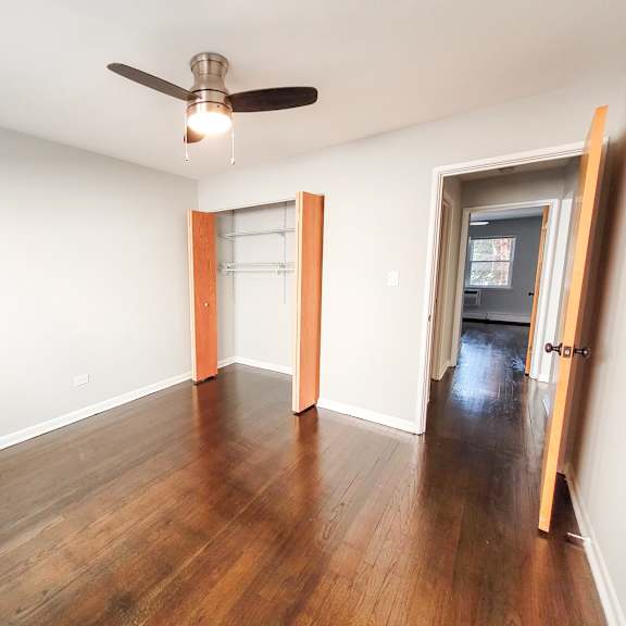 a room with a ceiling fan and wood flooring.