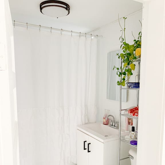 a white bathroom with a white shower curtain and a toilet