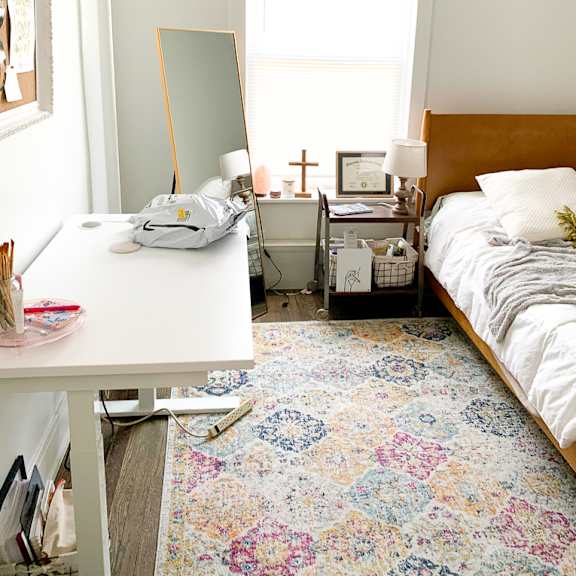 a small bedroom with a bed and a desk and a mirror