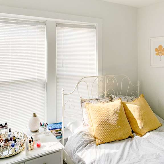 a bedroom with a bed with yellow pillows next to two windows