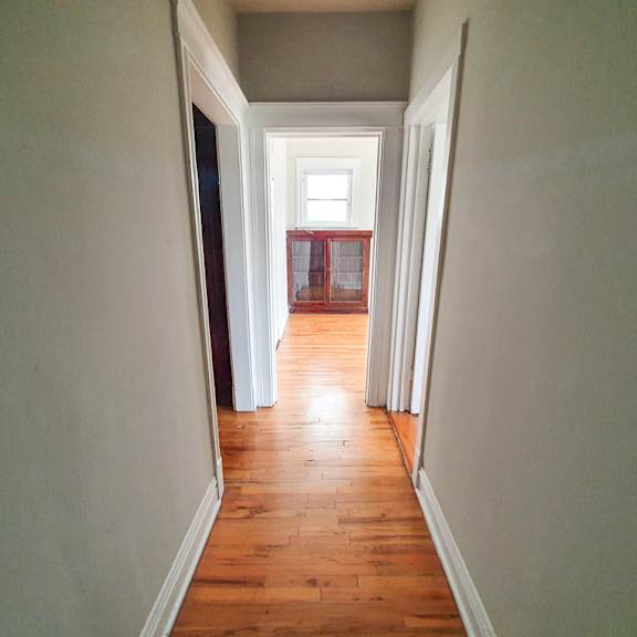 a long hallway with a wooden floor and white walls.