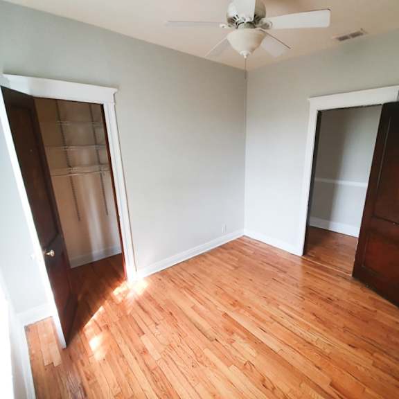 a room with a ceiling fan and wooden floors.