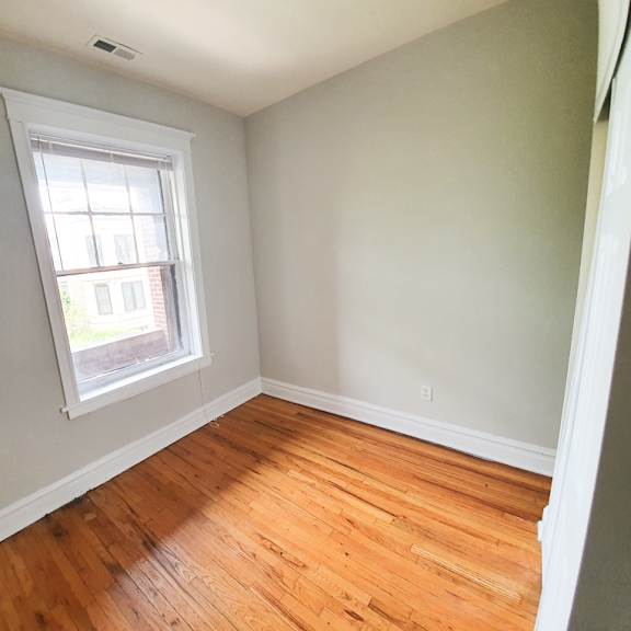 a room with a window and wooden floors.