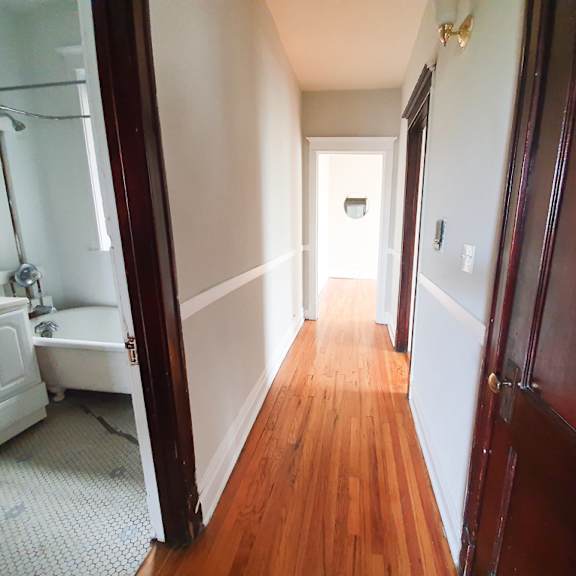 a long hallway with wood floors and white walls.