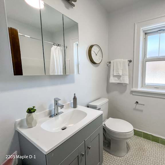 a bathroom with a white sink, toilet, and a window.