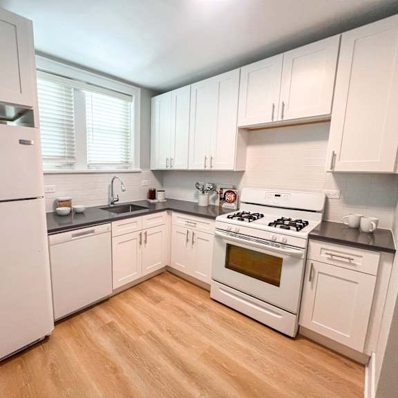a kitchen with white appliances and wooden floors.
