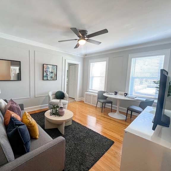 a living room with a grey couch and a ceiling fan.