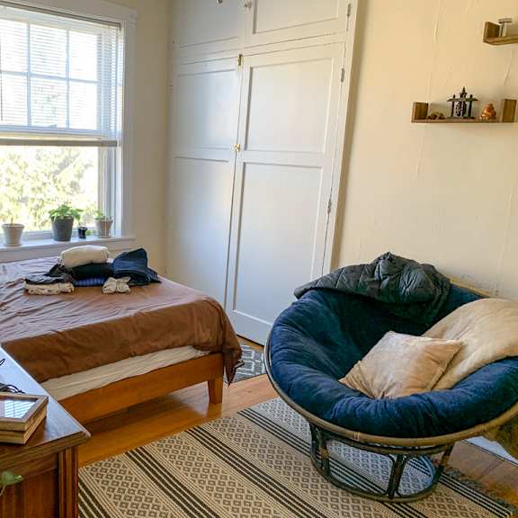 a room with a bed, a chair, and a potted plant.