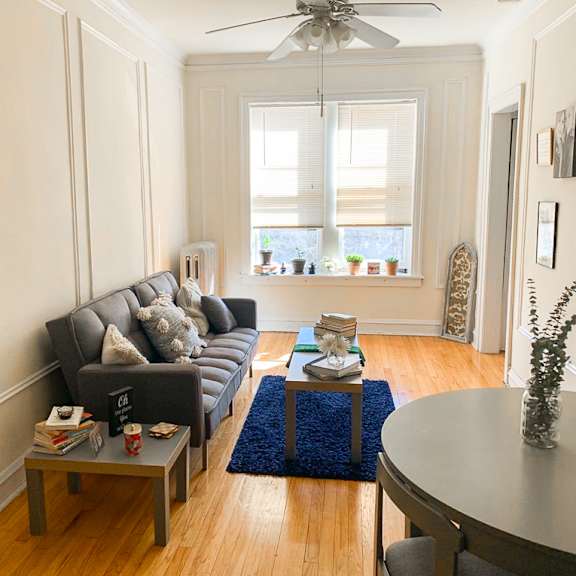 a living room with a grey couch, a coffee table, and a ceiling fan.