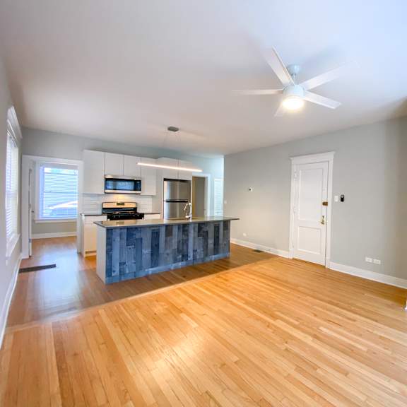 a spacious room with wooden floors and a ceiling fan.