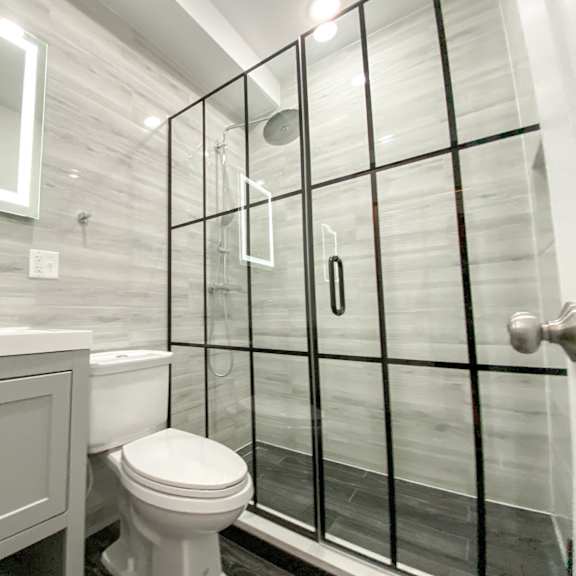 a white toilet sits in a bathroom with a glass shower door.