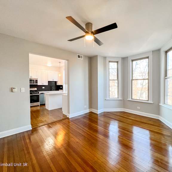 a spacious room with a ceiling fan and wooden flooring.