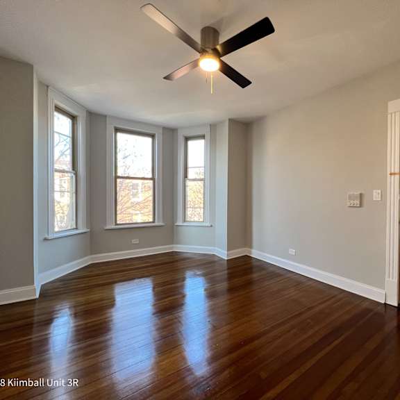 a room with a ceiling fan and wooden floors.