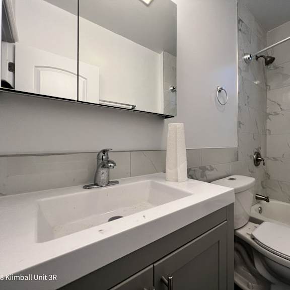 a white sink with a silver faucet and a toilet in a bathroom.