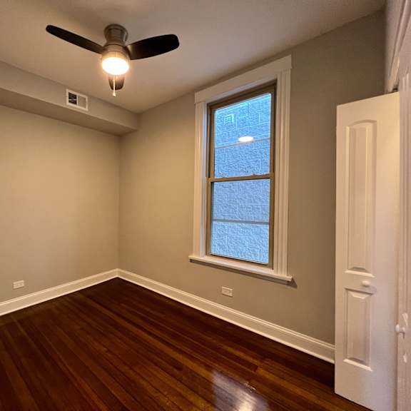 a room with a ceiling fan and a window.
