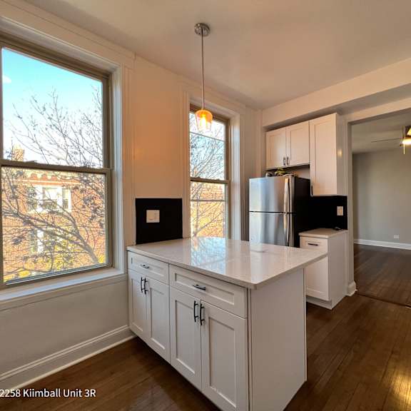 a kitchen with white cabinets and a black fridge.